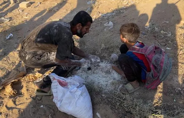 Un adulte et un enfant palestiniens récupèrent de la farine tombée au sol après un raid aérien israélien à Gaza, le 22 juillet 2025. Un adulte et un enfant palestiniens récupèrent de la farine tombée au sol après un raid aérien israélien à Gaza, le 22 juillet 2025.
